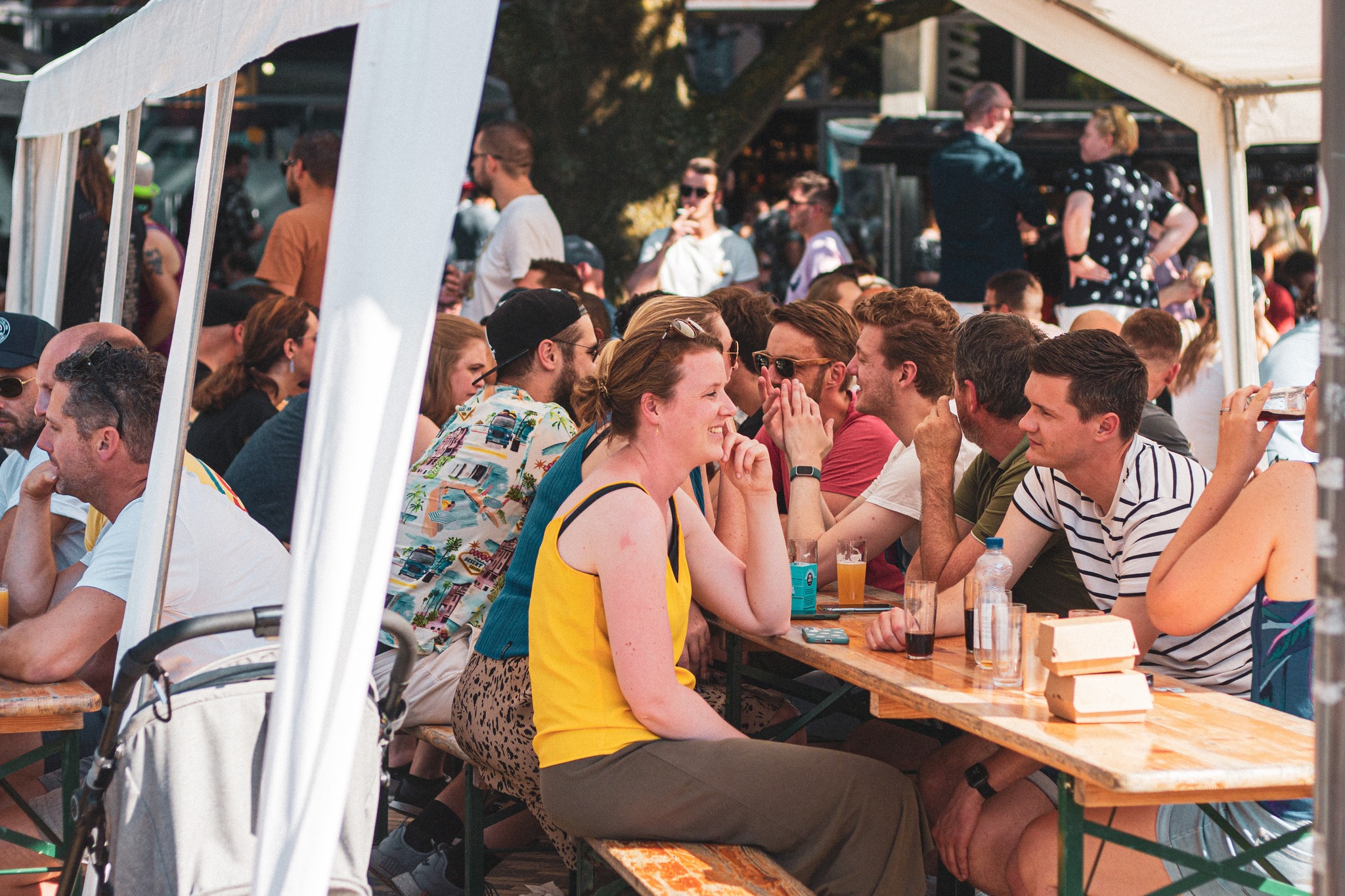 Bezoekers aan de biertafels onder de tent